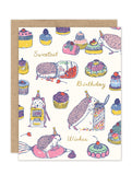 The Sweet Treats Hedgehog Birthday Card by Biely & Shoaf features colorful hedgehogs in party hats playing among cupcakes and sprinkles, with handwritten text that says "Sweetest Birthday Wishes." Artwork by Emily Taylor.