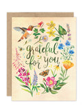 The Grateful Hummingbird Luxe Thank You Card by Biely & Shoaf features colorful flowers, a hummingbird, and a butterfly around the hand-lettered message "grateful for you" on a light background from the A2 Luxe Collection.