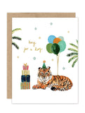 The Biely & Shoaf "King For A Day Tiger Luxe Birthday Card" is an eco-friendly A2 card featuring a tiger in a party hat with balloons, gifts, palm leaves, and stars. Gold foil details highlight the “king for a day” message.