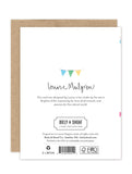 The back of the Birthday Banner Luxe Birthday Card by Biely & Shoaf displays a small colorful bunting illustration, Biely & Shoaf branding, and printed card and publisher details, including eco-certifications.