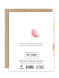 Back of the eco-friendly Wind Swept Blossoms Luxe Birthday Card by Biely & Shoaf, featuring a pink flower, gold foil accents, an uplifting quote on connection and joy, and exposed brown envelope edges against a white background.