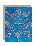 The Biely & Shoaf Celestial Burst Luxe Birthday Card features a blue background, gold foil "Wishing you a magical birthday," and illustrated branches with multicolored leaves and stars.