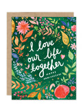 The I Love Our Life Together Luxe Anniversary Card by Biely & Shoaf features colorful flowers and leaves on green, with white handwritten text: “I love our life together. Happy Anniversary.” Printed on eco-friendly stationery.