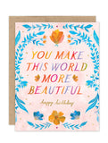 The More Beautiful Luxe Birthday Card by Biely & Shoaf features “You make this world more beautiful” in rainbow letters, surrounded by watercolor flowers, with "Happy Birthday" in gold script at the bottom.