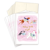 The Biely & Shoaf Dogs Making Spirits Bright Boxed Holiday Cards feature four dogs in festive sweaters on a pink background with stars and gold foil accents. "Making Spirits Bright" is on the front. FSC-certified. Blank envelopes included.