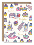 Sweet Treats Hedgehog Birthday Card by Biely & Shoaf features hedgehogs in party hats with cupcakes and cakes—one reading a cookbook, another sprinkling a cake. Gold foil on FSC-certified recycled paper. Perfect for the sweetest birthday wishes!.