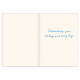 The Ribbon Best Mom Award Mother's Day Card by Biely & Shoaf is an open gold foil card with a cream background. The right page reads "Celebrating you, today and every day" in blue cursive; the left page is blank. Printed on FSC-certified recycled paper.