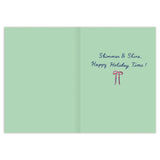 Open card with a light green background. Right page shows blue script text: "Reindeer Deck the Halls, Happy Holiday Time!" above a small red and white bow, with elegant gold foil accents. Left page is blank. From Biely & Shoaf's Boxed Holiday Cards collection.