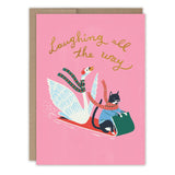 The Laughing All The Way Swan & Cat Holiday Card by Biely & Shoaf features a swan and cat in scarves sledding together on a pink background, with gold foil text above—a cheerful design for your holiday greetings.