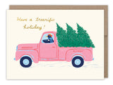 The Biely & Shoaf Tree-rific Penguin In Truck Boxed Holiday Cards, set of 10, features a pink truck with green Christmas trees and a penguin driver, plus “Have a treerrific holiday!”—perfect for eco-friendly greetings.