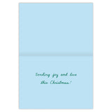 The inside of a Biely & Shoaf Tree-rific Penguin In Truck holiday card set features recycled paper and the handwritten green message, Sending joy and love this Christmas! Box contains 10 light blue cards.