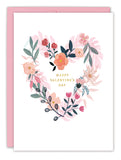 The Biely & Shoaf Floral Heart Valentine's Day Card features a heart-shaped wreath of pink, red, and coral florals with greenery, framing gold-foil "Happy Valentine’s Day" text on white card stock. Includes a pink envelope.