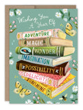 The Biely & Shoaf A Year of Wishes Book Stack Birthday Card features a stack of colorful books labeled Adventure, Magic, Imagination, and more, surrounded by flowers, butterflies, and a bee with gold foil accents and Wishing You A Year Of.