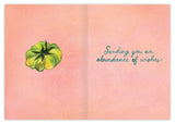 The Tomatoes Birthday Card by Biely & Shoaf features a green tomato on the left and Sending you an abundance of wishes in blue cursive on a soft pink patterned background. Printed in the USA.