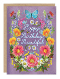 The Prairie Flowers Birthday Card by Biely & Shoaf features "Happy Birthday Beautiful" in cursive on a purple background, with vibrant flowers, a blue butterfly, a bee, and gold foil accents inspired by Katie Daisy’s whimsical style.