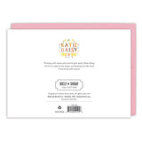 The back of the Love Birds Valentine's Day Card by Biely & Shoaf with pink envelope features a floral Katie Daisy logo, artist info, Biely & Shoaf Collection details, barcode, and product info—printed in the USA.