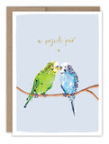 The Biely & Shoaf Parakeets Anniversary Card features a green and blue parakeet perched together with a perfect pair and a heart above, finished with gold foil—an ideal card for anniversaries.