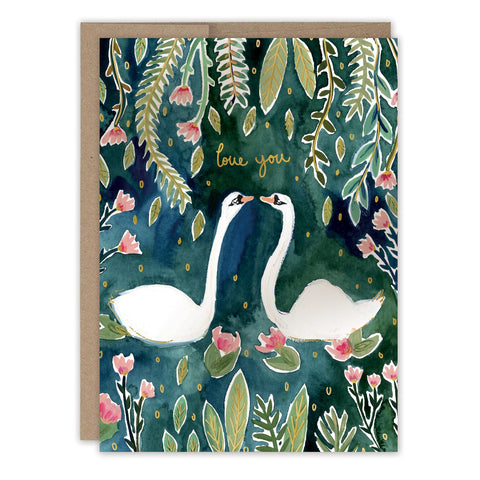Two white swans face each other on a dark green background with leaves and pink flowers. "Love you" appears in gold foil above them on the front of this Biely & Shoaf Swans Love Card.