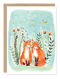 The Foxes Anniversary Card by Biely & Shoaf features two illustrated foxes beneath stars and a crescent moon, surrounded by flowers. "I love you" appears in gold foil on a light blue background—a perfect choice for anniversaries.
