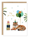 The King For A Day Tiger Birthday Card by Biely & Shoaf features a tiger in a party hat beside stacked presents and balloons, with greenery, gold foil stars, and "king for a day" above the tiger.