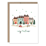 The Little Christmas Village Boxed Holiday Cards by Biely & Shoaf feature colorful houses, people, snowflakes, Christmas trees, and a red car on a snowy street with "Merry Christmas" below. Printed on recycled paper—perfect for holiday card sets.