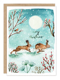 Two bunnies dash through snow under a full moon on Biely & Shoaf's Bunnies Merry Christmas Holiday Card Set.