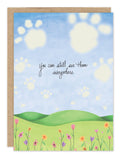 The Clouds Pet Sympathy Card by Biely & Shoaf features a grassy hill, wildflowers, and paw prints in a blue sky. The card’s message reads, “You can still see them everywhere.”.