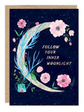The Inner Moonlight Birthday Card by Biely & Shoaf showcases a crescent moon with blue and green leaves and pink flowers on a starry sky. Gold foil text reads "FOLLOW YOUR INNER MOONLIGHT," inspired by Meera Lee Patel's whimsical style.
