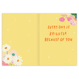 The Sunshine Mother's Day Card by Biely & Shoaf features a yellow design with white polka dots, colorful corner flowers, and the message "Every day is brighter because of you" in orange script. Designed by Meera Lee Patel and printed in the USA.
