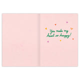 The Wild Thing Valentine's Day Card by Biely & Shoaf is an open pink greeting card, printed in the USA, with Meera Lee Patel’s "You make my heart so happy!" in green and colorful hearts on the right side.